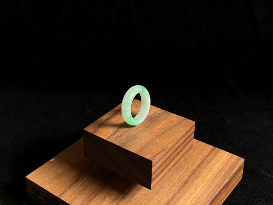 An icy white jadeite ring adorned with two accents of vibrant green.