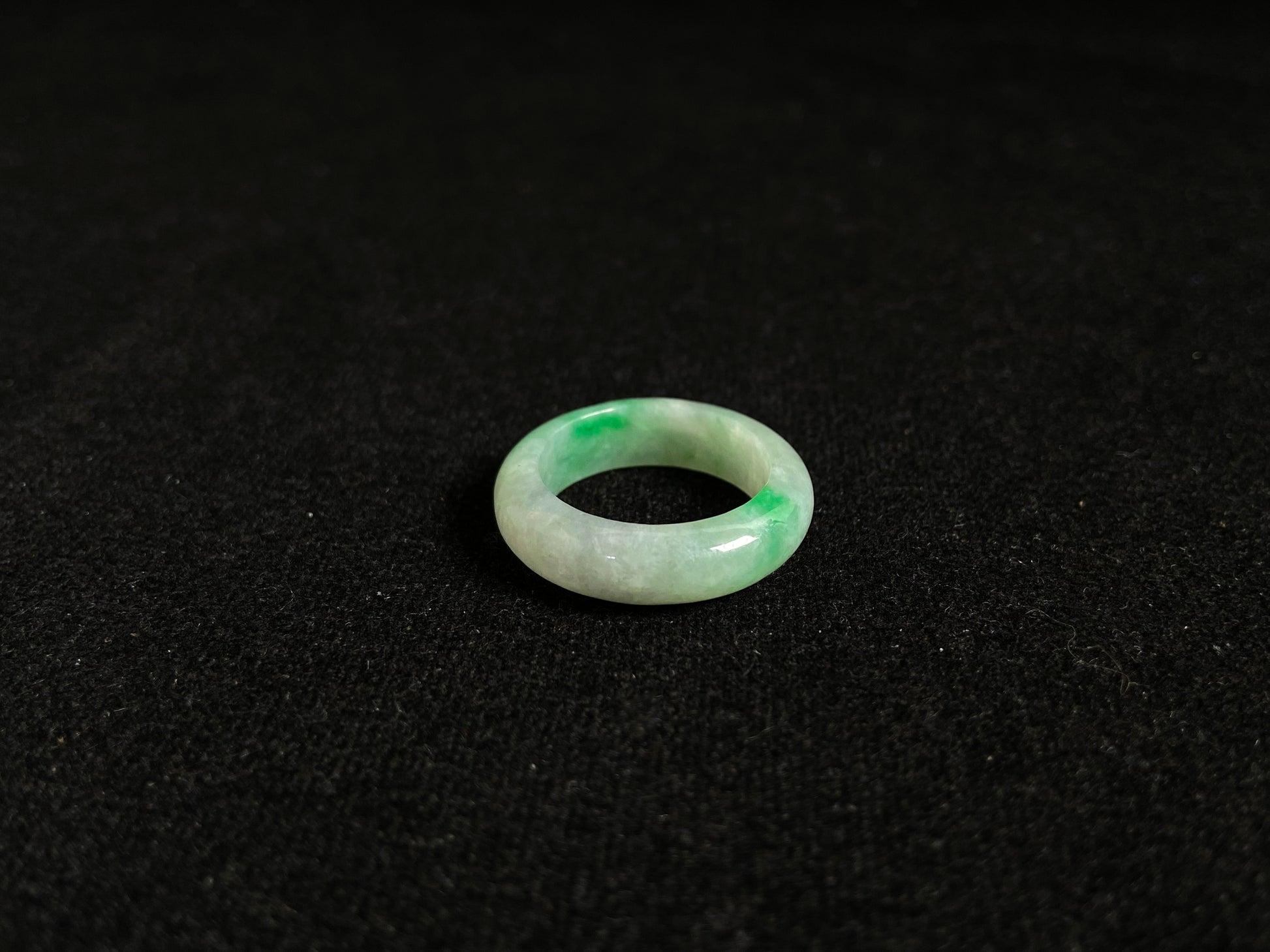 An icy white jadeite ring adorned with two accents of vibrant green.