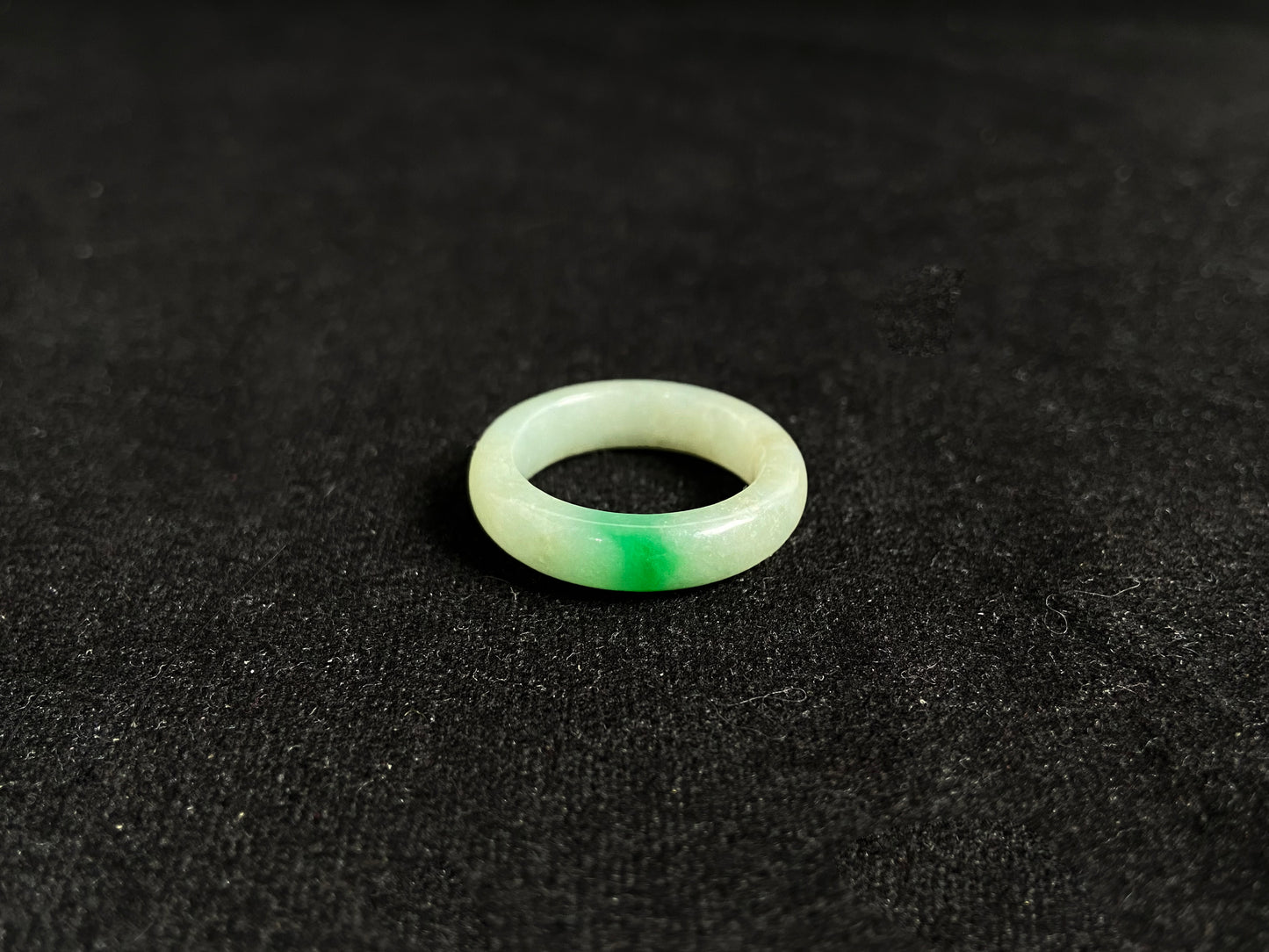 A milky white jadeite ring adorned with floating green accents.