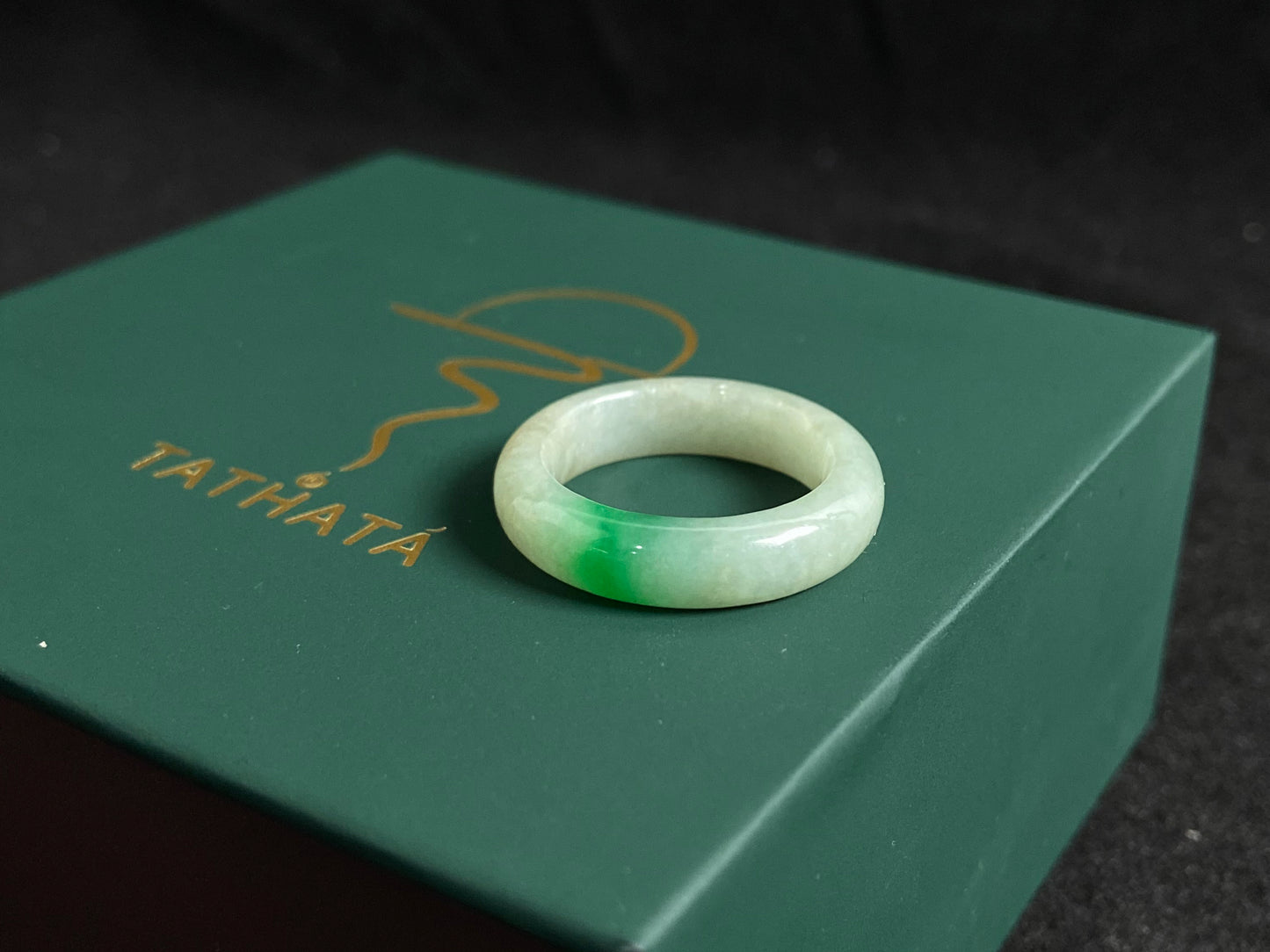 A milky white jadeite ring adorned with floating green accents.