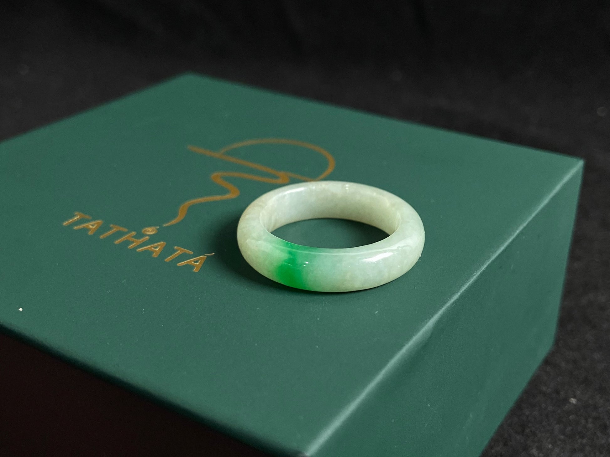A milky white jadeite ring adorned with floating green accents.