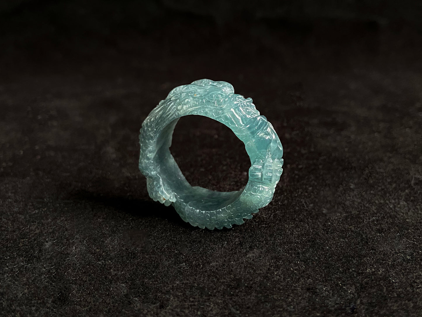 This elegant ring showcases a translucent light green jadeite carved with a majestic dragon motif.