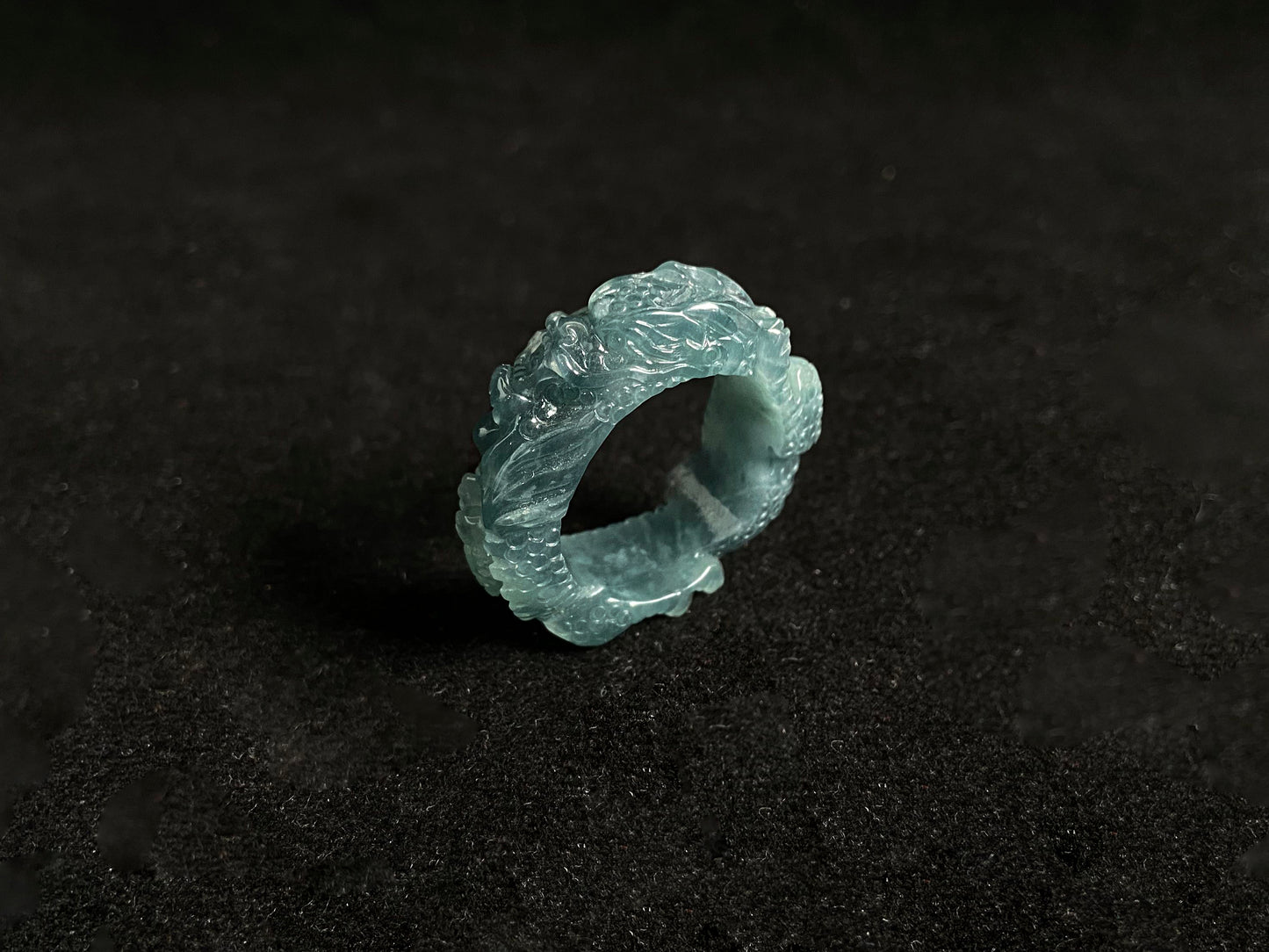 This elegant ring showcases a translucent light green jadeite carved with a majestic dragon motif.