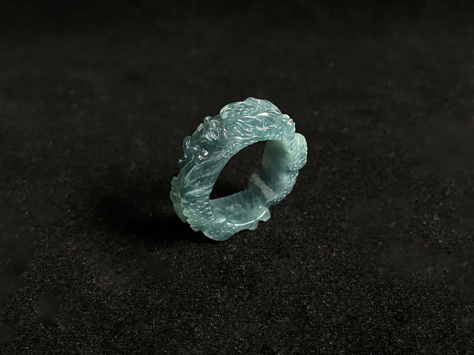 This elegant ring showcases a translucent light green jadeite carved with a majestic dragon motif.