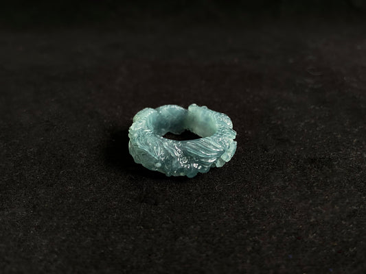 This elegant ring showcases a translucent light green jadeite carved with a majestic dragon motif.