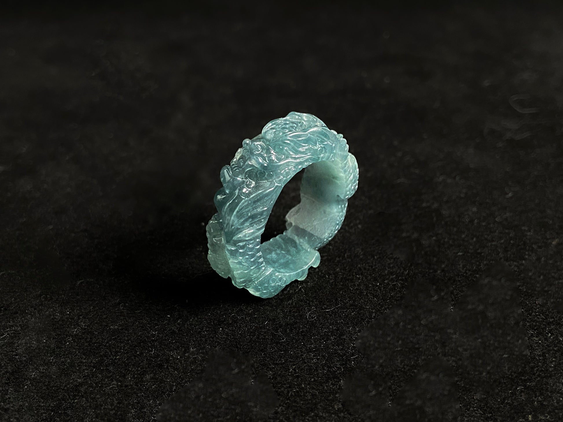 This elegant ring showcases a translucent light green jadeite carved with a majestic dragon motif.