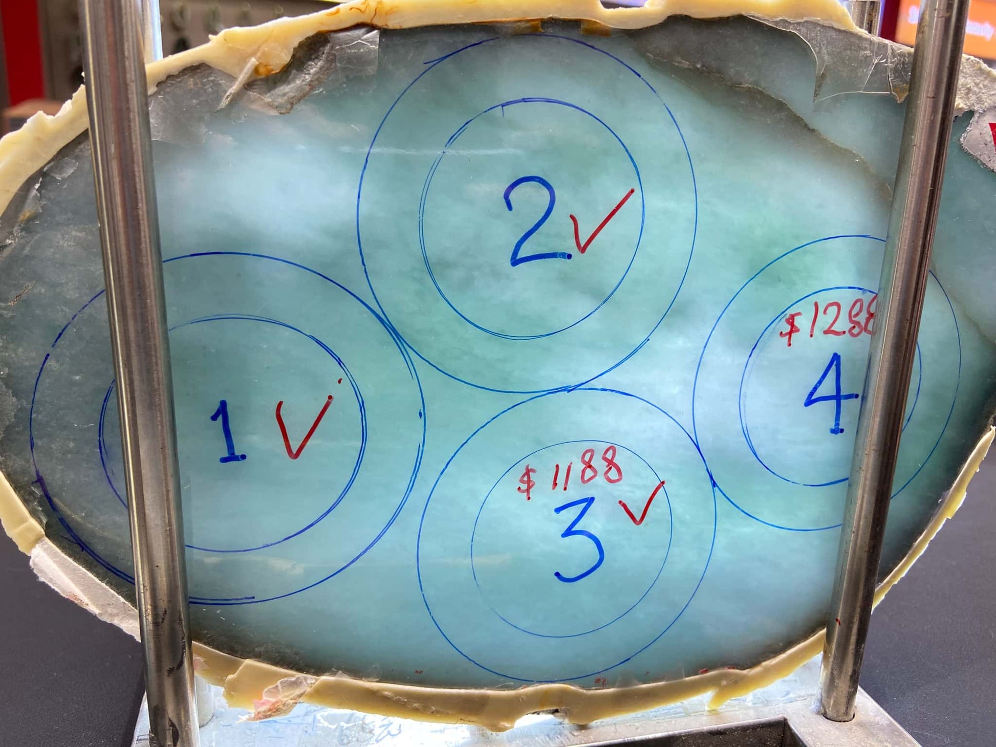 Glass block with numbers and symbols drawn on it, held by metal bars. Multi-purpose Carving of Jadeite Rough Stones & Custom Bangle Services