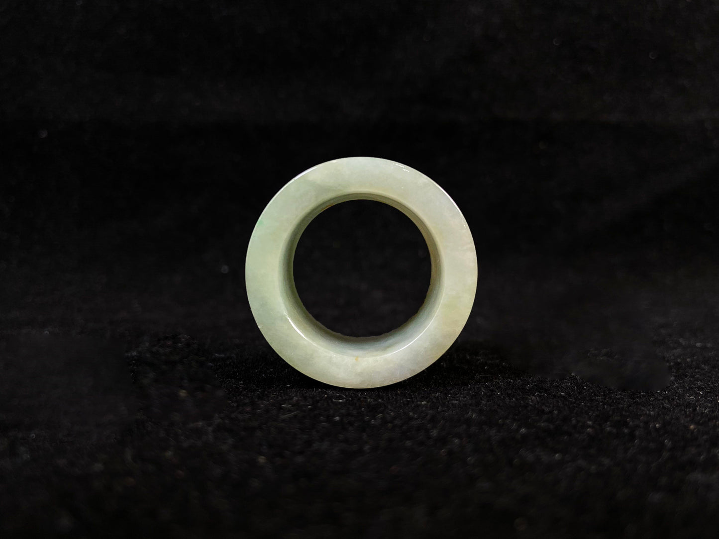 A light green jade thumb ring with golden undertones.