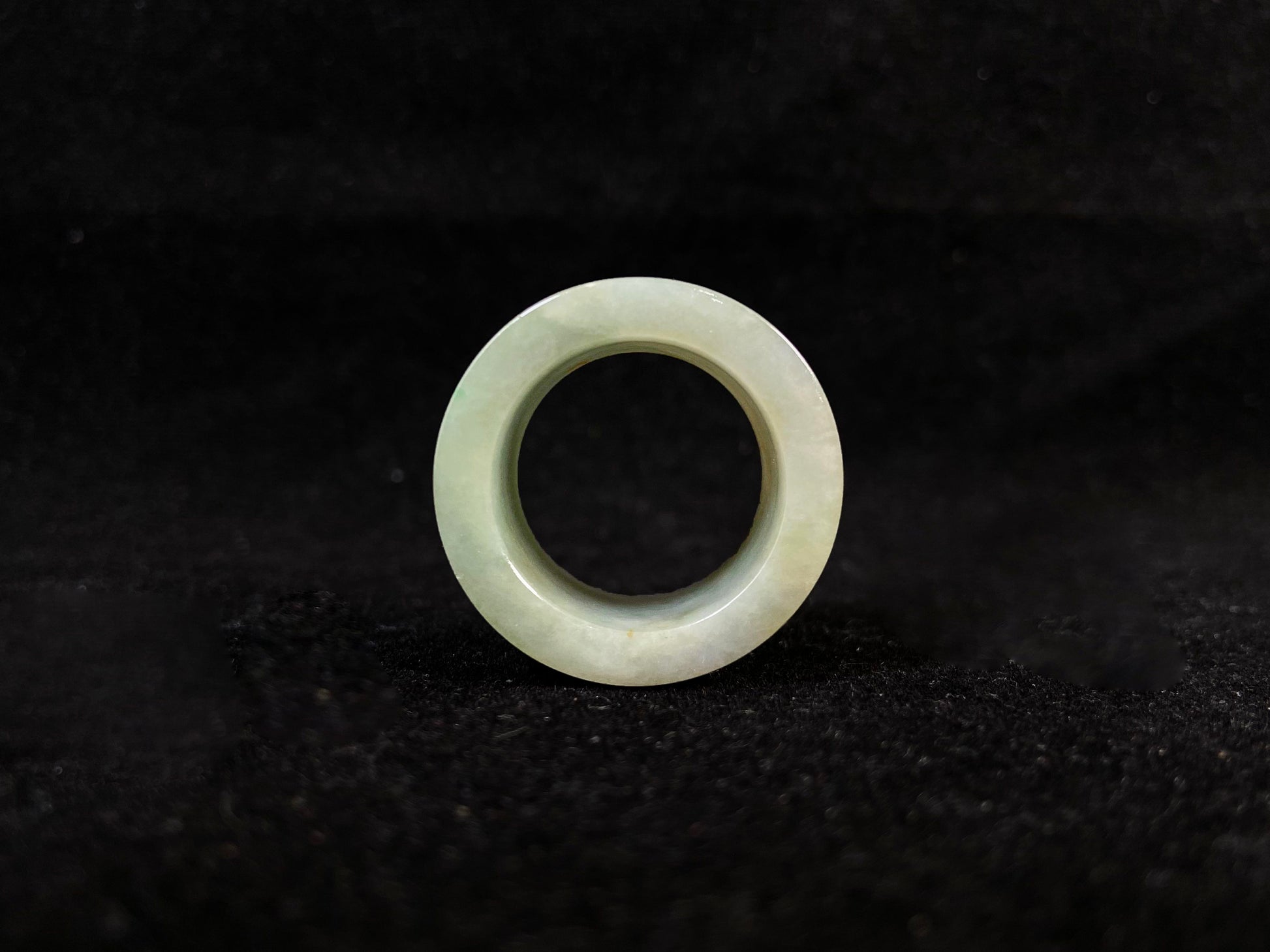 A light green jade thumb ring with golden undertones.