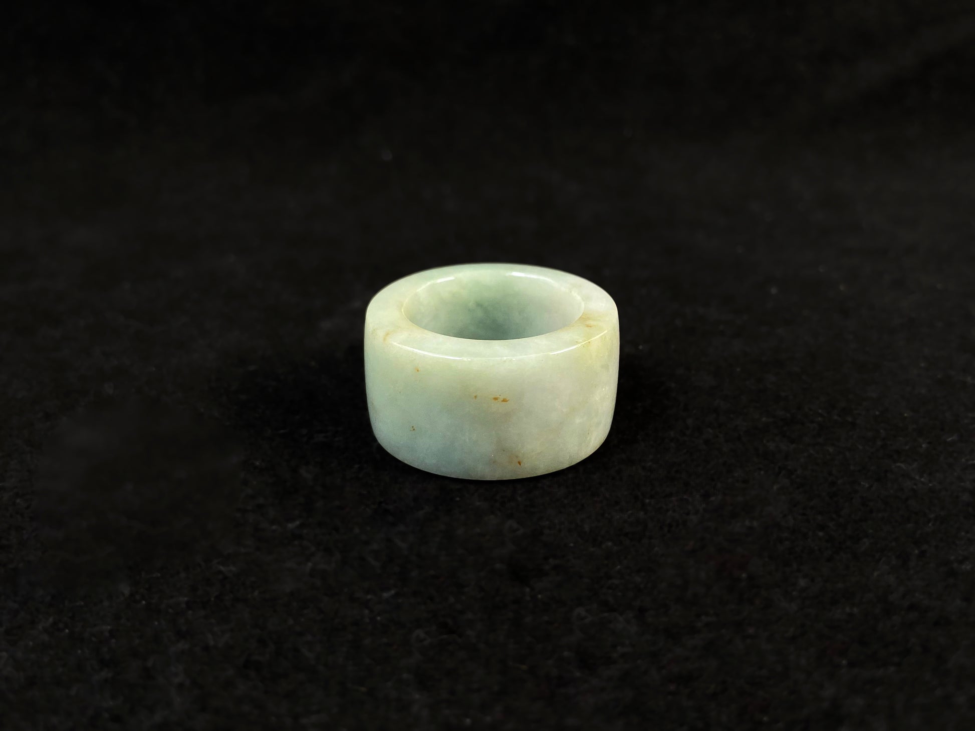 A light green jade thumb ring with golden undertones.