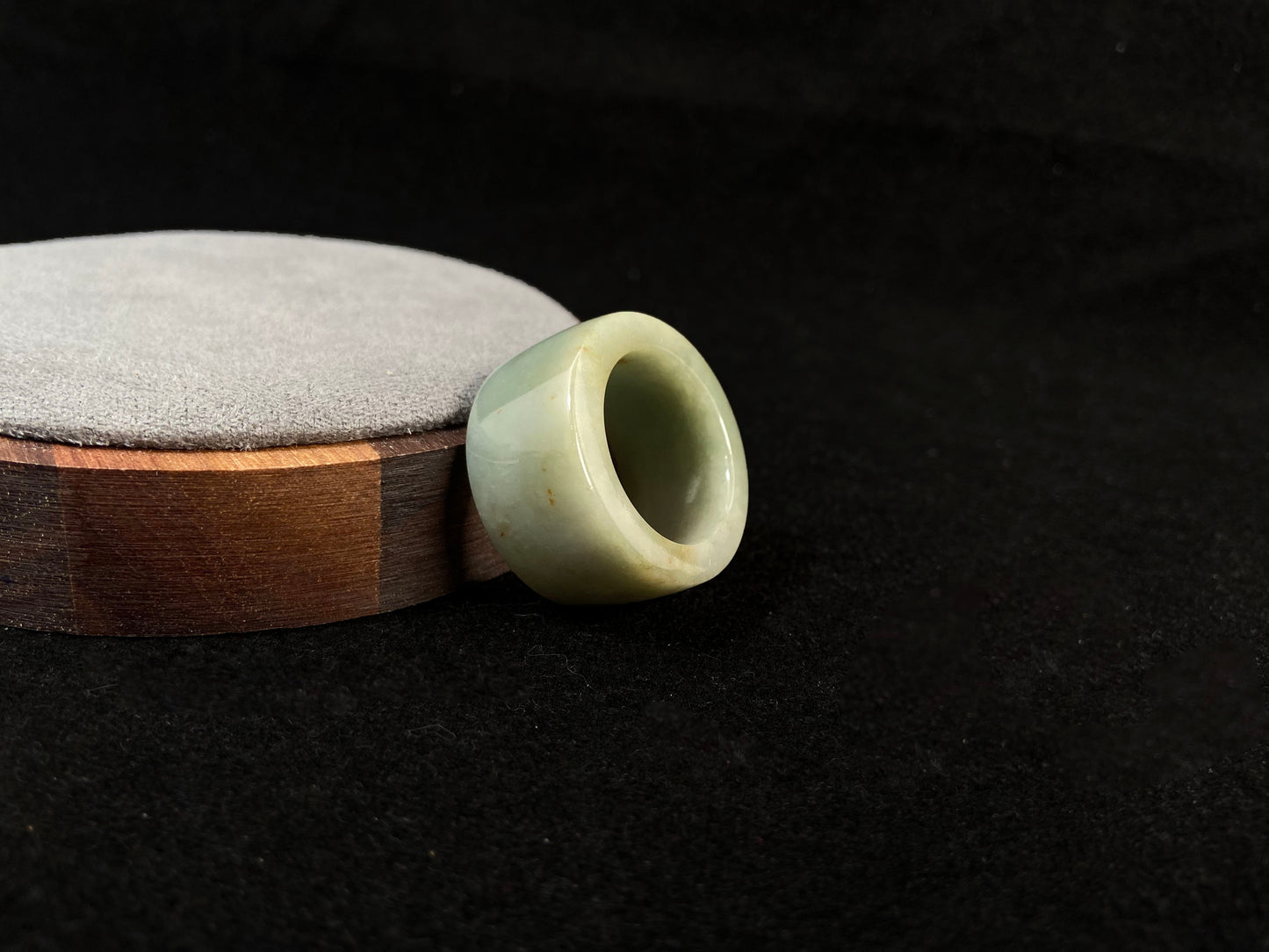 A light green jade thumb ring with golden undertones.