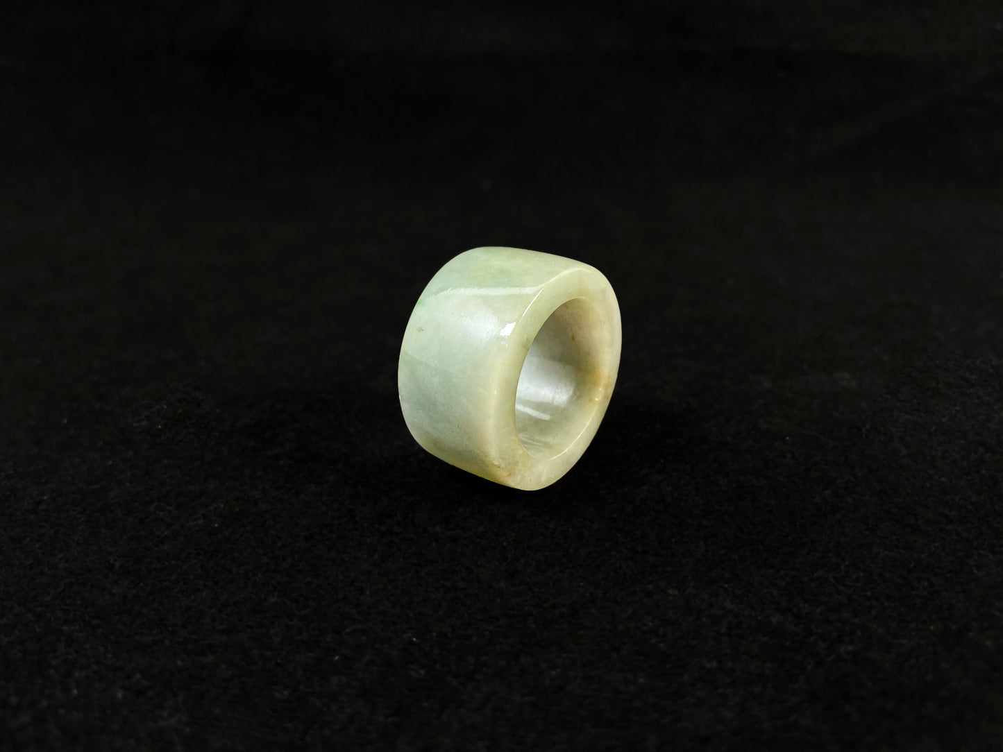 A light green jade thumb ring with golden undertones.