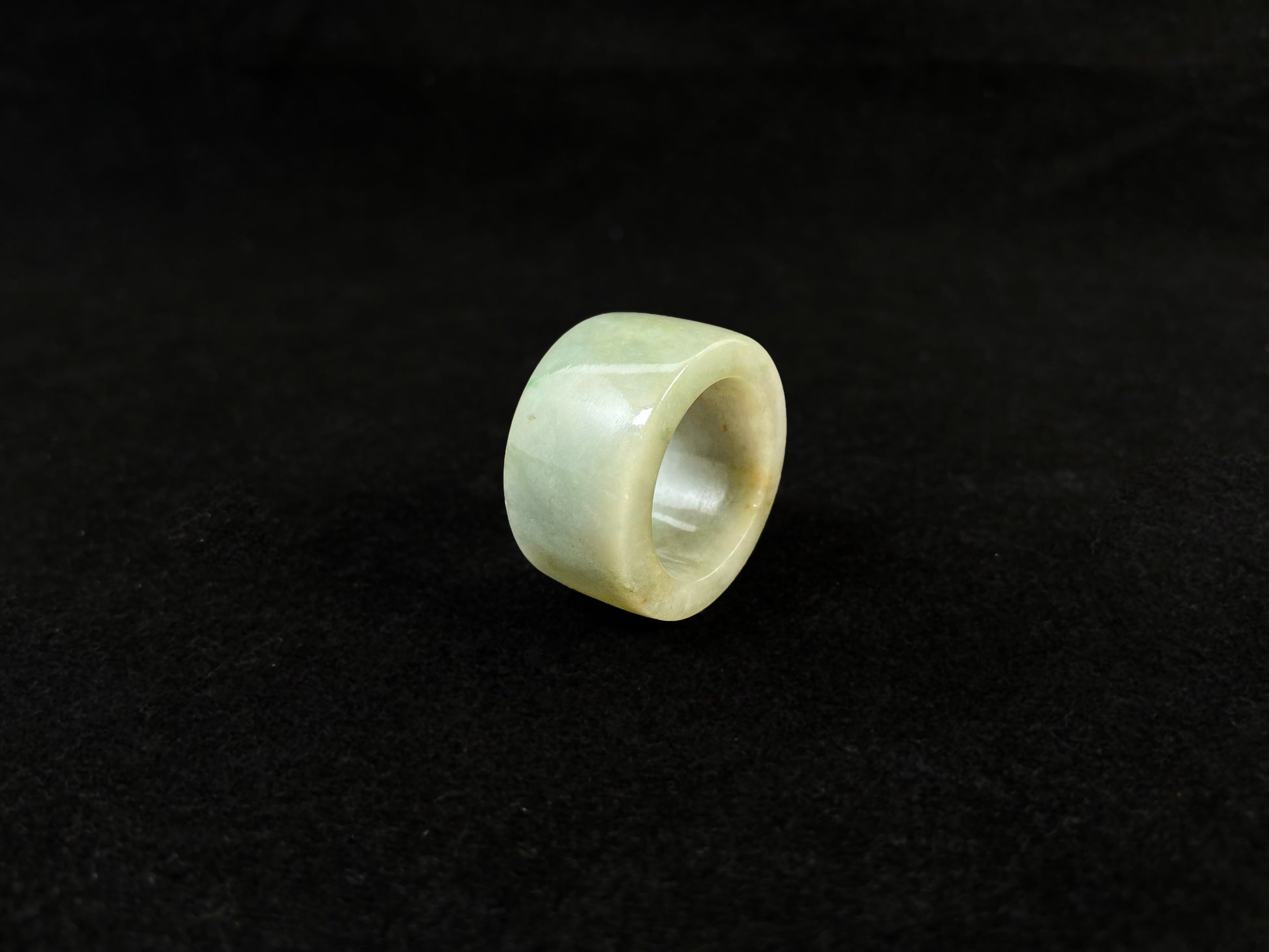 A light green jade thumb ring with golden undertones.