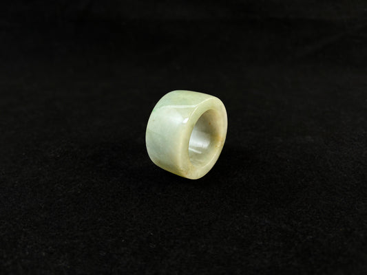 A light green jade thumb ring with golden undertones.