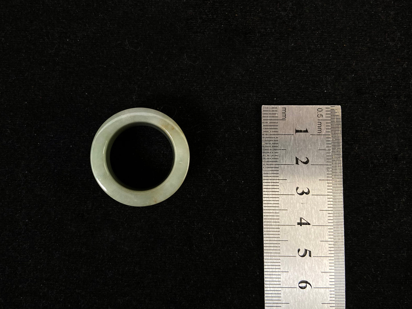 A light green jade thumb ring with golden undertones.