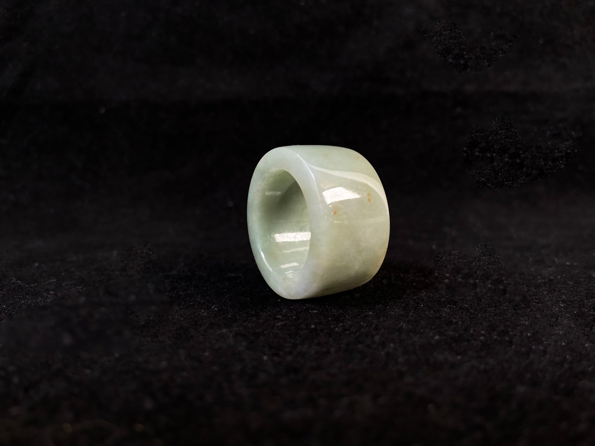 A light green jade thumb ring with golden undertones.