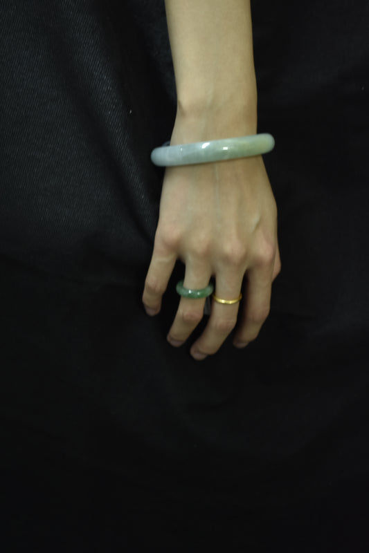 Model wearing a natural violet jadeite round bangle with gold rings, highlighting its elegance and translucency.