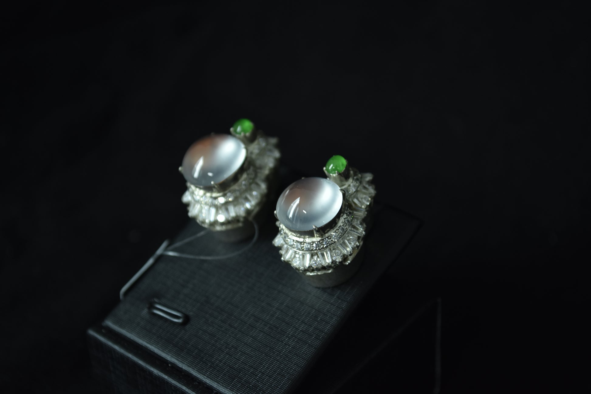Pair of silver earrings with green gemstones on a dark background